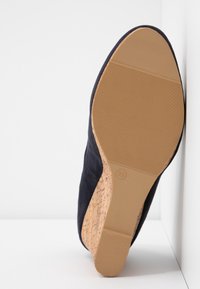 Vue de la semelle d'une chaussure compensée marine avec un talon en liège, taille 39, sur un fond blanc d'angle.