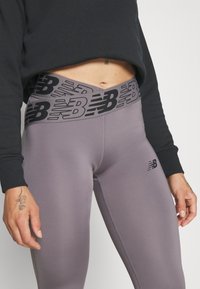 Obcisłe, szare legginsy z czarnym pasem z logo. Charakteryzują się gładką teksturą i subtelnych detalami w szwie, idealne do użytku aktywnego.