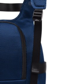 Mochila de malla azul con una superficie texturizada, cremalleras negras, correas ajustables y un diseño elegante y moderno.