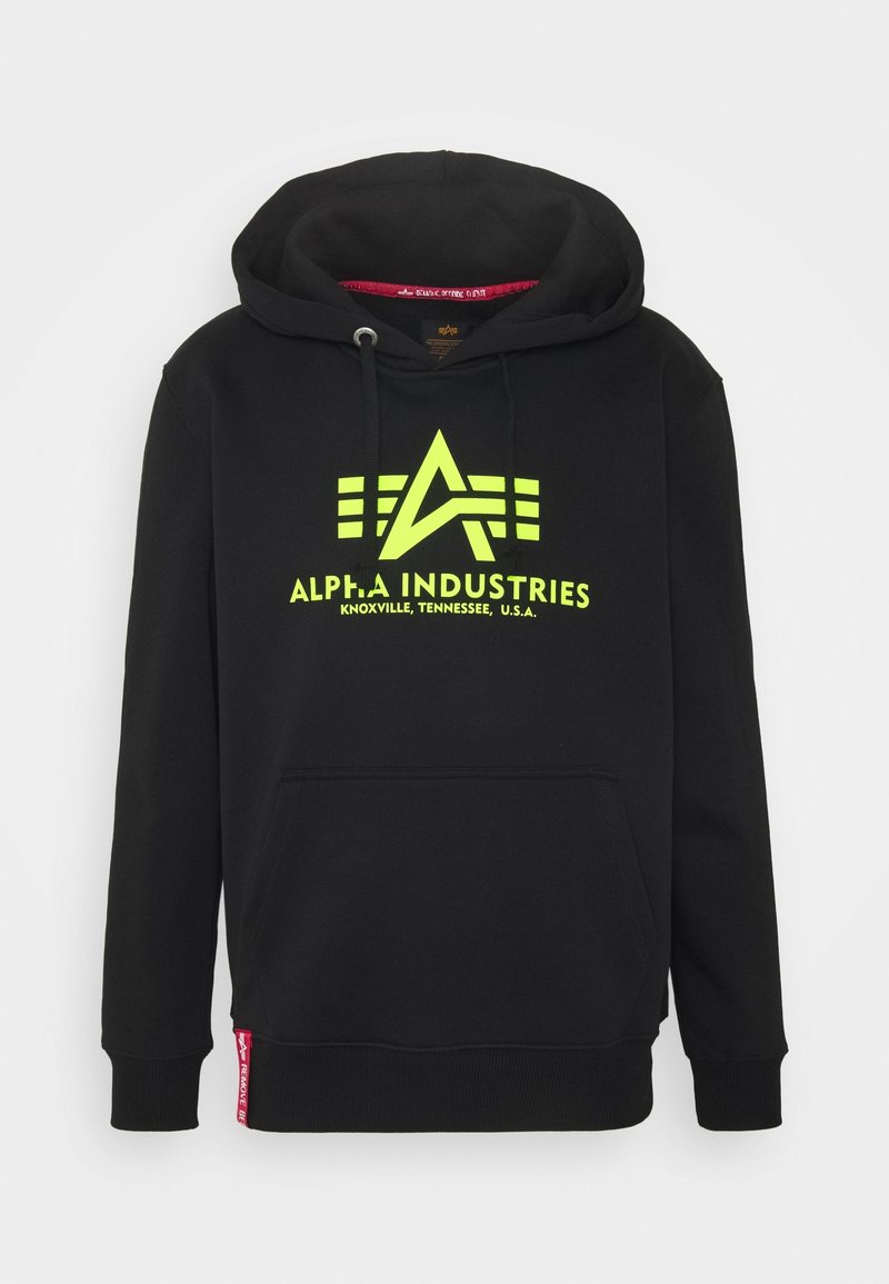 Sudadera negra con capucha de la marca Alpha Industries, logo y texto en amarillo neón que dice "Knoxville, Tennessee, U.S.A." Con bolsillo tipo canguro en la parte delantera y cordón para la capucha.