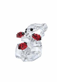 Číry krištáľový medveď, ktorý drží tri červené lienky s čiernymi detailmi. Má hladký povrch, facétovanú textúru a zaoblený tvar.