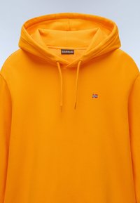 Oranje hoodie met een trekkoord in de capuchon, met een klein geborduurd vlaglogo op de borst. Zachte stof met een gladde textuur.