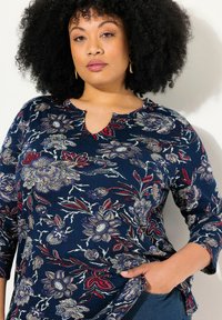 Marineblaue Bluse mit Dreiviertelärmeln, Ausschnitt mit Schlüssellochdesign, Blumendruck in Beige, Rot und Lila, aus weichem Stoff gefertigt.