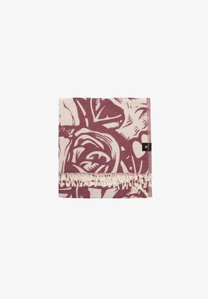 Foldet beige og malva stof med abstrakt blomsterprint og fryns, med lille sort og gul mærkeetiket.