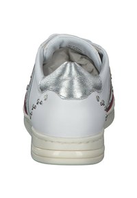 Zapatilla blanca con acentos plateados en el talón, parte trasera texturizada y tachuelas decorativas a lo largo del costado. Plantilla acolchada visible desde la abertura.