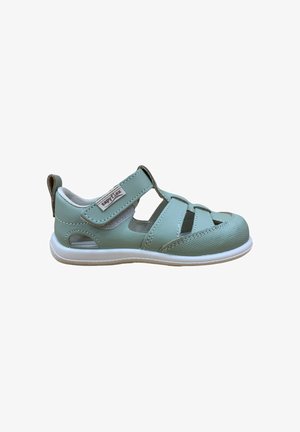 Sandalia para niños de color azul claro con punta cerrada, tira ajustable, suela blanca y pequeños detalles recortados en los lados y la parte superior.