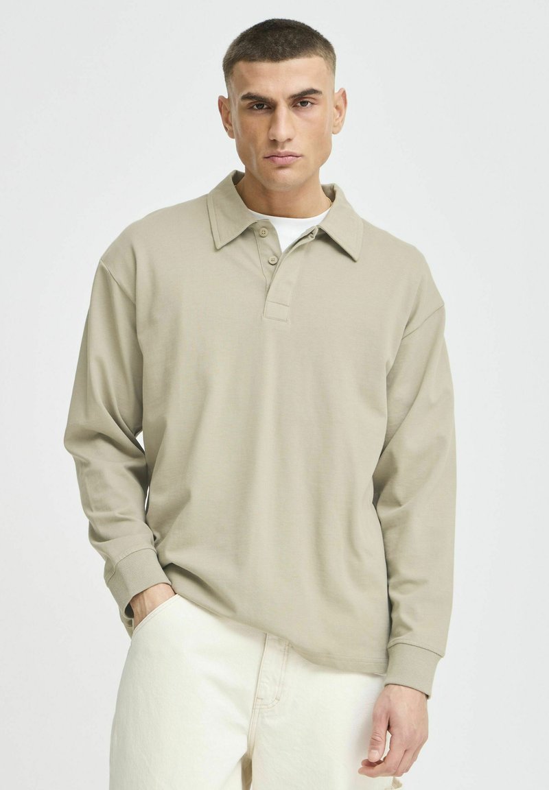 Lichtbeige poloshirt met lange mouwen, een klassieke kraag, een drie-knopen sluiting en geribbelde manchetten, gecombineerd met crèmekleurige broek.