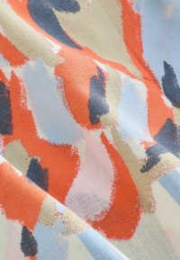 Model abstract de țesătură cu tușe neregulate în nuanțe de portocaliu, albastru, bej și negru, pe o suprafață texturată de pânză.