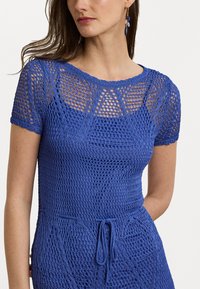 Abito blu lavorato a maglia con un motivo in tessuto aperto e testurizzato, maniche corte e vita regolabile con cordino. Vestibilità aderente con scollatura rotonda.
