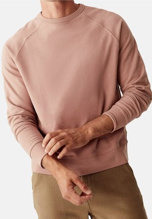 Sweatshirt rose clair à col rond, avec des manches longues, des poignets côtelés et une coupe décontractée, fabriqué en tissu doux en mélange de coton.
