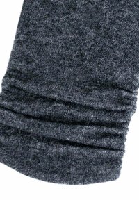 Tissu tricoté gris avec une texture douce, affichant un design froncé au niveau du poignet. La surface présente de légères variations de tons de couleur.