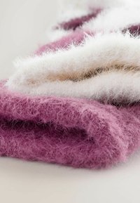 Foldede tekstiler i bløde hvide og lyserøde nuancer, der har en fluffy tekstur med fine fibre, hvilket skaber et hyggeligt og taktilt udseende.