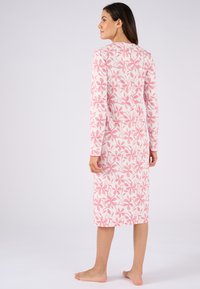 Vestido de noche de manga larga y hasta los tobillos en rosa claro con un patrón floral. Está hecho de una tela suave y cuenta con un cuello redondo y puños lisos.
