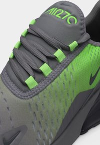 Γκρι και πράσινο αθλητικό παπούτσι με πράσινους κρίκους κορδονιών, γκρι κορδόνια, κείμενο «Air270» στη γλώσσα και μαύρο λογότυπο Nike στο πλάι.