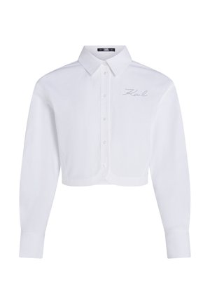 Balts īsā piedurkņu krekliņš ar garām piedurknēm, ar klasisku apkakli un diskrētu izšūtu logotipu uz krūtīm. Gluda auduma tekstūra.