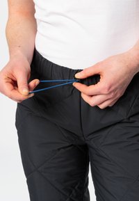 Pantalons noirs matelassés avec une taille élastique et un cordon bleu en cours d'ajustement par une main. Tissu lisse et léger.