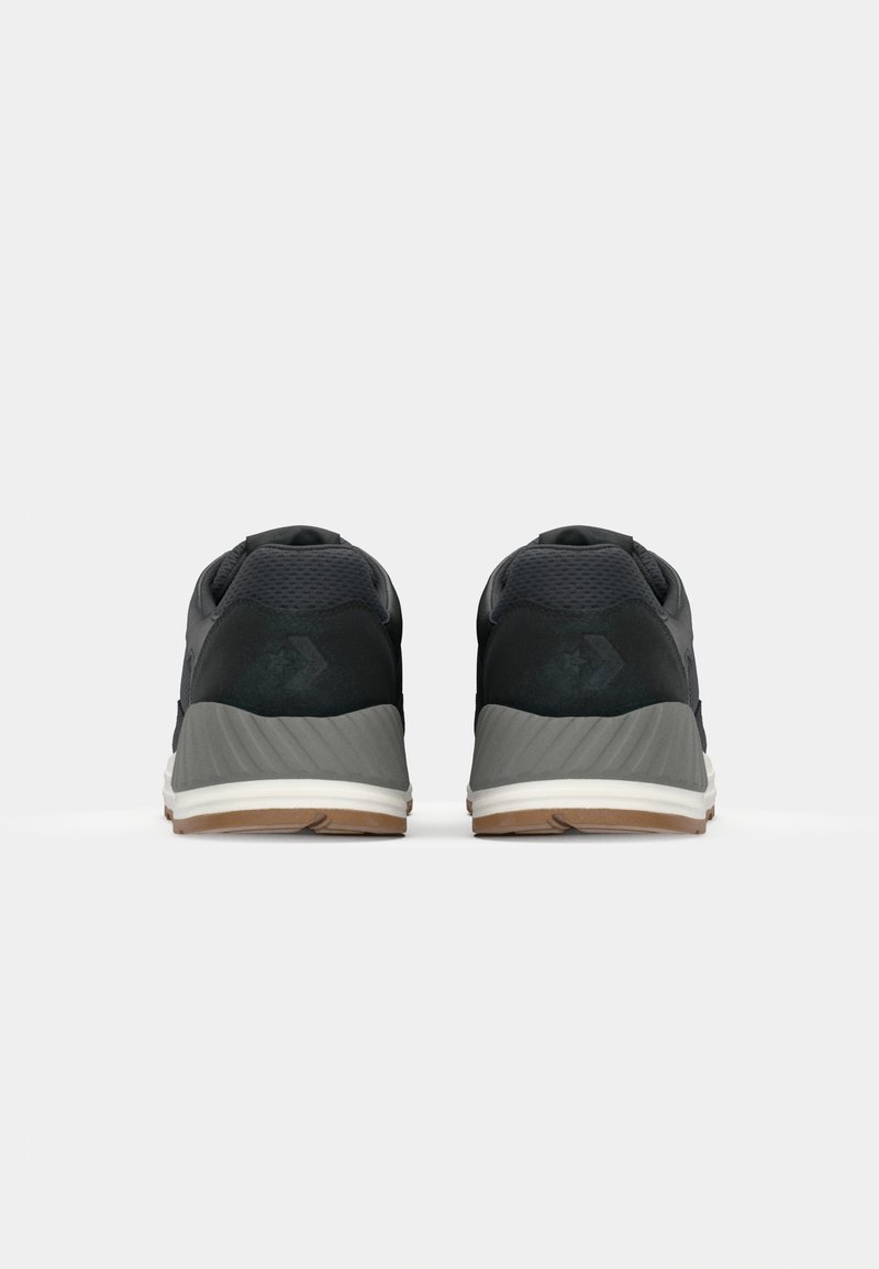 Scarpe sportive nere con tomaia in rete testurizzata, suola intermedia grigia e suola in gomma. Presentano un ammortizzatore nel tallone e un branding minimale.