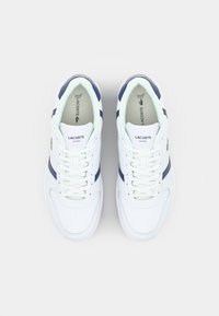 Zapatillas blancas con acentos en azul marino, materiales de cuero y sintéticos, puntera redonda, diseño con cordones y un logo verde en el lateral.