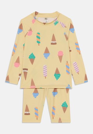 Ensemble de bain pour enfants en deux pièces de couleur jaune, avec des motifs de cônes de glace et de popsicles. Haut à manches longues et short en tissu doux et extensible.