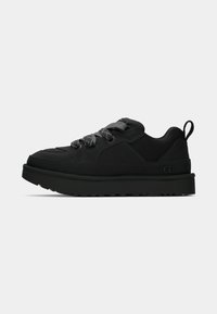 Black sneaker with a textured fabric upper and smooth synthetic accents. Features flat laces, a padded collar, and a thick rubber sole.
