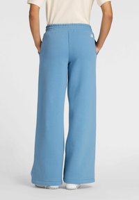 Light blue wide-leg sweatpants with an elastic waistband, textured fabric, and side pockets, featuring a small logo on the back.