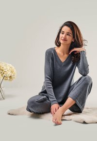 Gray knit loungewear set featuring a V-neck sweater and wide-leg pants, soft texture, ribbed detailing on sleeves, and relaxed fit.