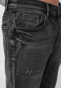 Μαύρο τζιν από denim με σχέδιο πέντε τσεπών, ελαφριά φθορά και απαλό ύφασμα. Διαθέτει αντίθετη ραφή και μέση μεσαίου ύψους.