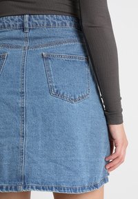 Jeansrock in Hellblau mit fransigem Saum, verfügt über zwei Gesäßtaschen und eine taillierte Passform, hergestellt aus weichem, strukturiertem Denim-Stoff.