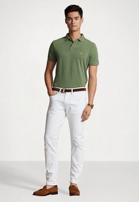 Green polo shirt with a collar, beige belt, white pants, and brown loafers. Casual fit with a subtle texture and embroidered logo on the chest.