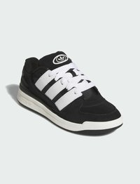 Zapatilla negra con rayas blancas, parte superior de cuero y textil, puntera redonda, suela plana, cordones blancos y detalle del logo en la lengüeta.