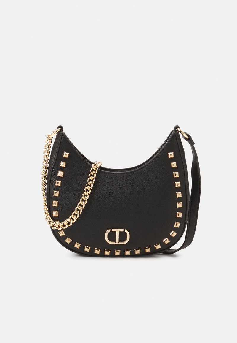 Sac à bandoulière en cuir synthétique noir avec des accents cloutés dorés, forme incurvée et bandoulière chaîne, avec une plaque logo à l'avant.