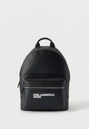 Czarny skórzany plecak z przednią kieszenią na zamek błyskawiczny oraz białym logo "KARL LAGERFELD JEANS" na kieszeni na białym tle.