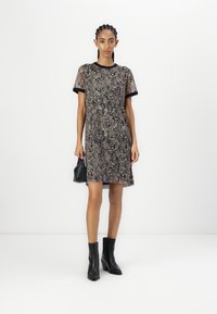 Lyhythihainen mekko käärmeennahkakuosisessa kankaassa, jossa on pyöreä pääntie, mustat reunat ja suora leikkaus. Yhdistetty ankle-boots-kengillä ja pienellä laukulla.