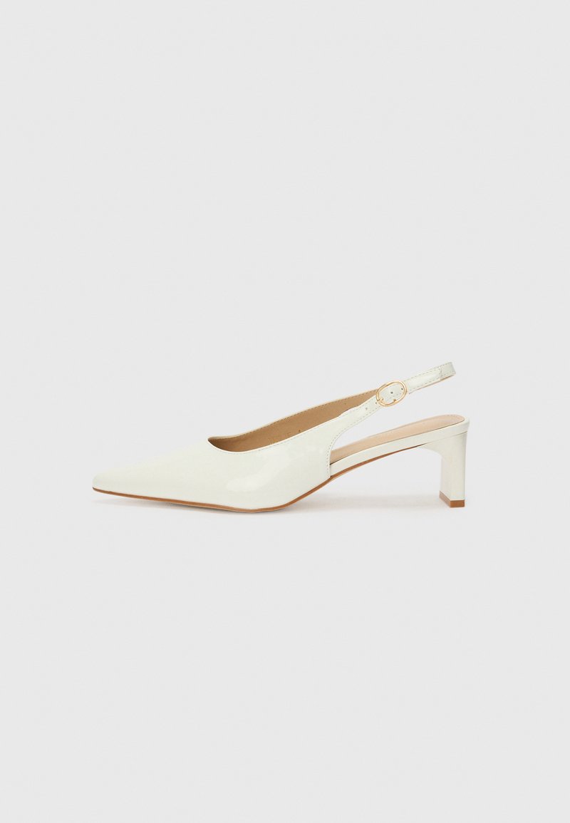 Valkoinen patenttilahja slingback-kengä, jossa on terävä kärki ja matala lohkokorko. Varustettu huomaamattomalla hihnalla, jossa on kultasävyinen solkiyksityiskohta.