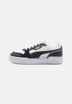 Schwarz-weiße Sneaker mit einem glatten Lederoberteil, strukturierten Akzenten, Schnürdesign und einer dicken weißen Gummisohle mit Logodetail.