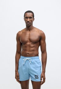 Világoskék fürdőnadrág húzózsinóros derékrésszel, bal oldalon fekete "HUGO" logóval. Simább anyagból, laza fazonban.