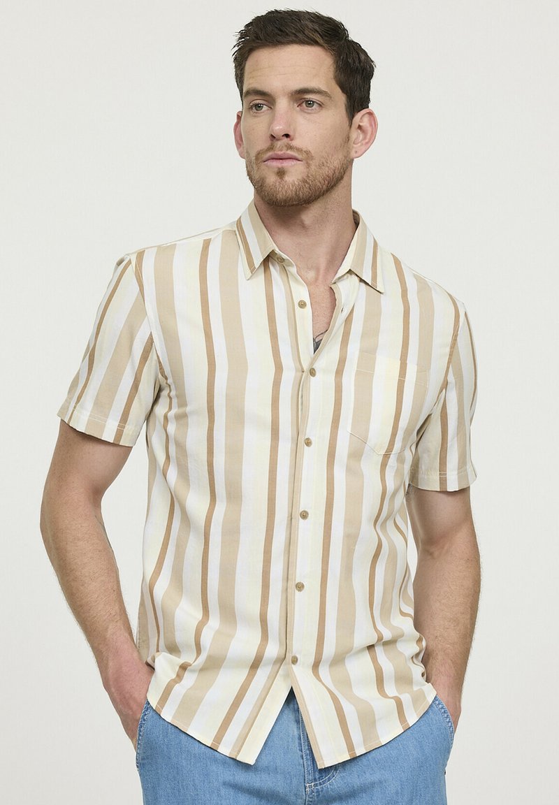 Chemise à manches courtes de couleur beige clair avec des rayures verticales crème et marron. Dotée d'un devant boutonné et d'une poche poitrine. Matière en coton.