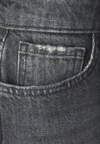 Tumšs denim audums ar redzamu aizmugures kabatu, kas lepojas ar izsistām malām un kontrastējošiem diegiem. Auduma virsma ir gluda ar nelielām krāsu variācijām.