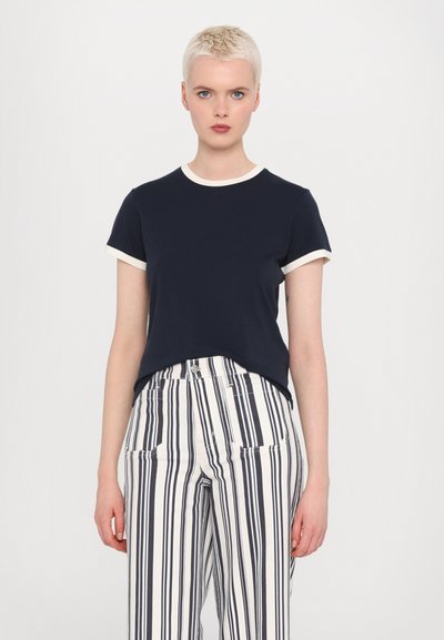 T-shirt navy a maniche corte con rifiniture color crema, abbinato a pantaloni a vita alta a righe navy e bianche, dotati di tasche frontali e gamba dritta.