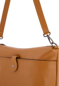 Tan leren handtas met een gladde textuur, afgeronde vorm en een afneembare schouderband met metalen hardware. Inclusief een drukknoopsluiting.