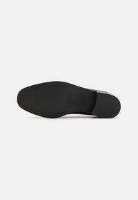 Svart sulan med en slät, något strukturerad yta. Har en rundad form, minimalistisk design och diskreta grepplinjer.