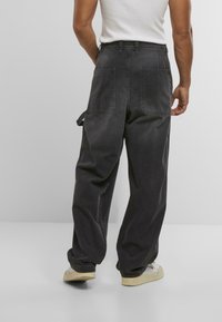 Zwarte denim cargobroek met een relaxed fit, voorzien van twee achterzakken, een zijzak voor gereedschap en verstelbare boorden.