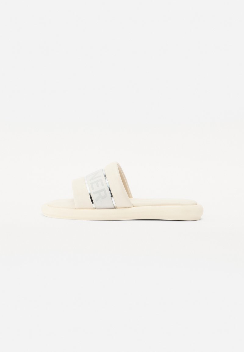 Sandales à glissière beige avec une large sangle ornée d'accents argentés et du mot "RUNNER". Semelle douce et rembourrée pour le confort. Texture lisse.