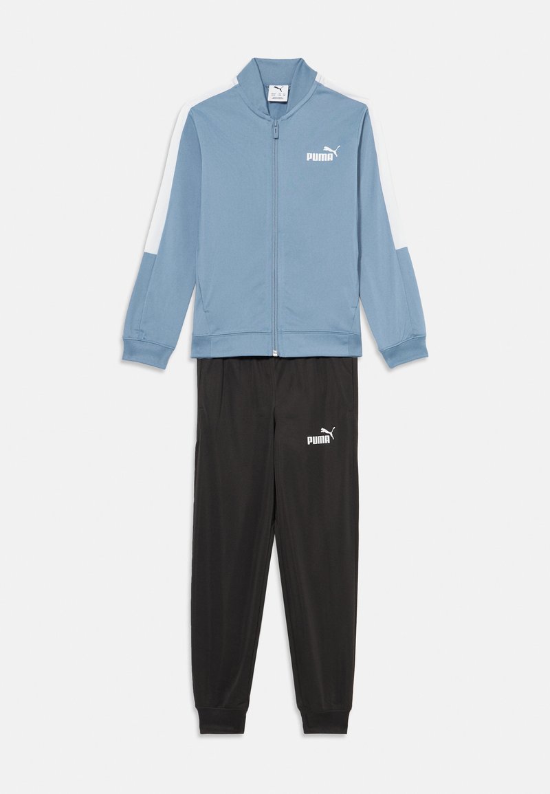 Veste zippée bleu clair avec des accents blancs et le logo Puma, associée à un pantalon noir arborant le logo Puma à la taille. Tissu lisse, coupe athlétique.