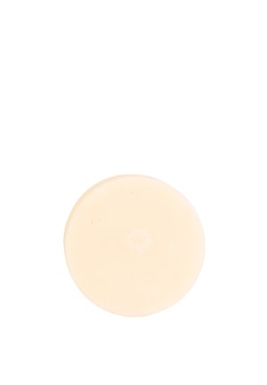 Barra di sapone solida rotonda beige con superficie liscia isolata su sfondo bianco.