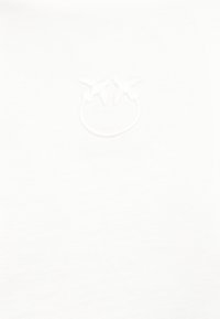 Λευκό ύφασμα με διακριτικό κεντητό σχέδιο ντομάτας κοντά στο πάνω κέντρο.