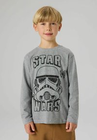 Hall halli pikkade varrukatega T-särk, millel on must graafiline kujutis tormisõdalase kiivrist ja tekst "STAR WARS". Pehme kangas, tavalise ümara kaelusega.