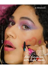 Närbild av ett ansikte med lila ögonskugga, rosa läppstift och hjärtformad rouge. Personen har lockigt hår och långa, färgglada naglar.