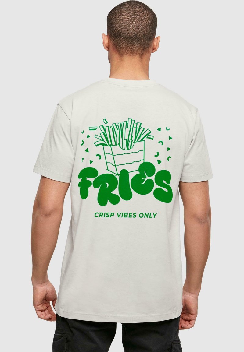 Jasnocreamowy bawełniany t-shirt z zielonym nadrukiem opakowania frytek z frytkami, w towarzystwie tekstu "FRYTKI" oraz "TYLKO WIBRACJE WYSTARSZĄ."