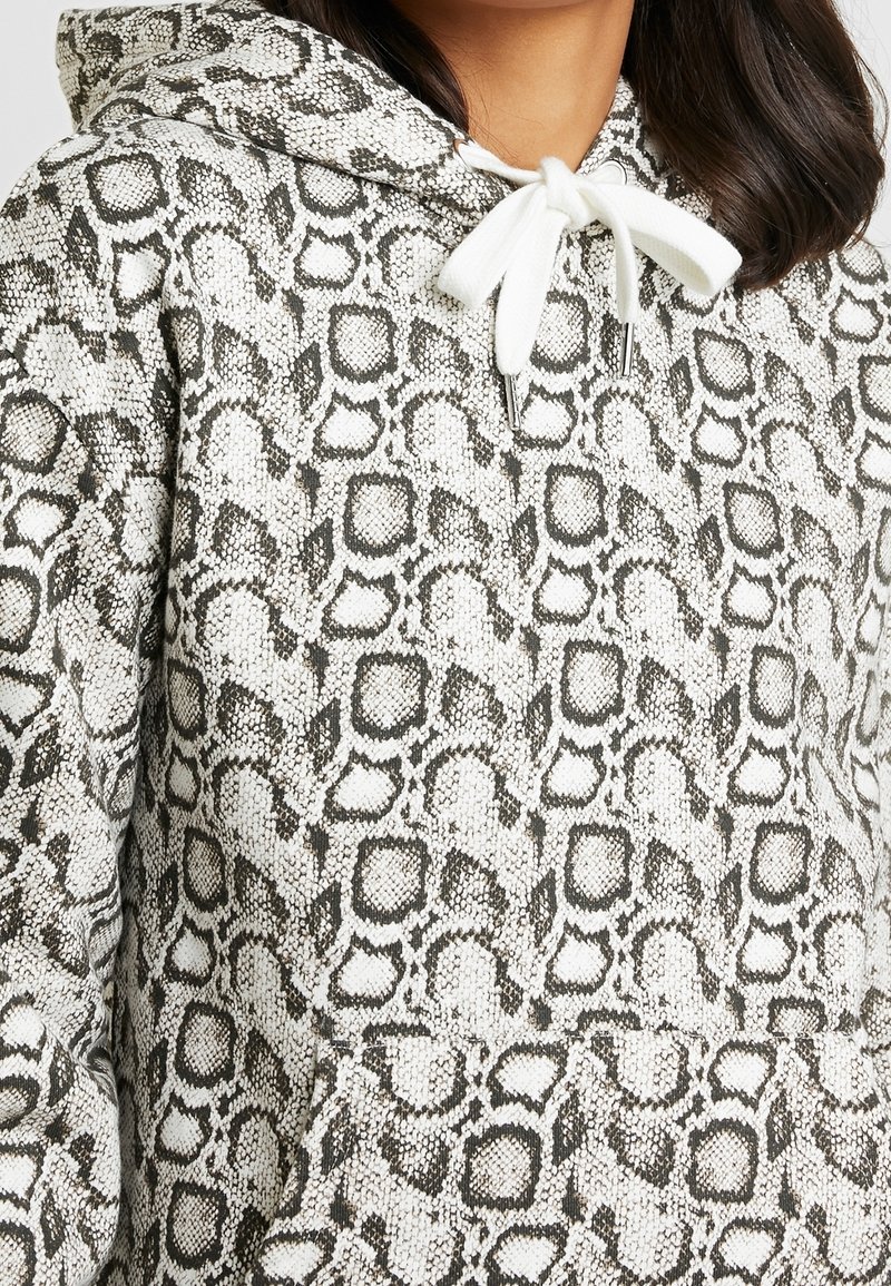 Mikina s kapucí z texturované látky s černobílým hadím vzorem. Obsahuje přední kapsu a stahovací šňůrku.